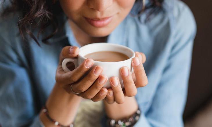 image of woman holding cup of coffee with both hands