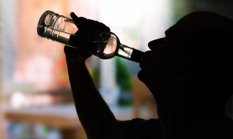 Silhouette of a man chugging a half-empty bottle