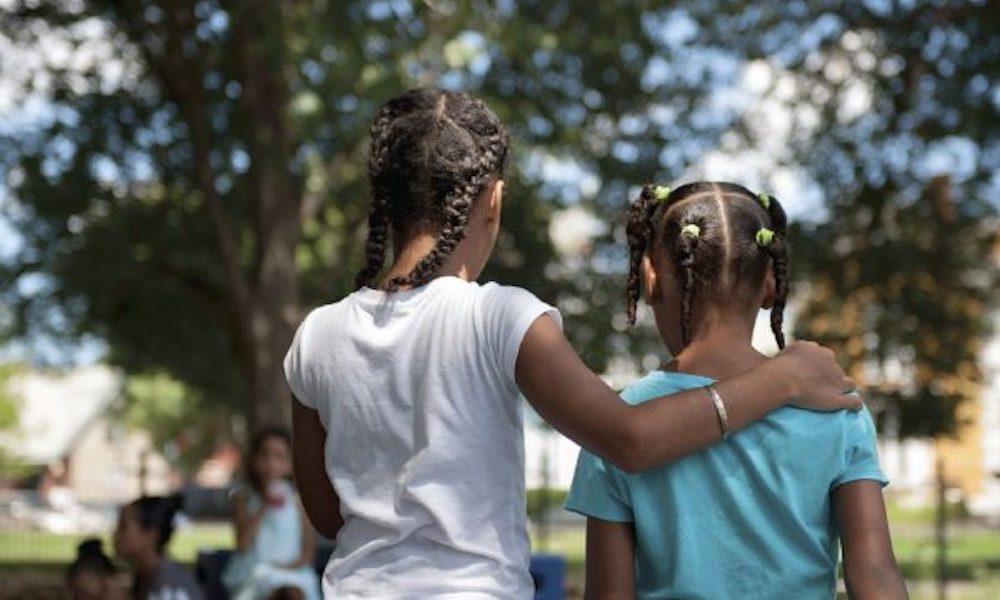 Two young African American girls walking with their arms around one another