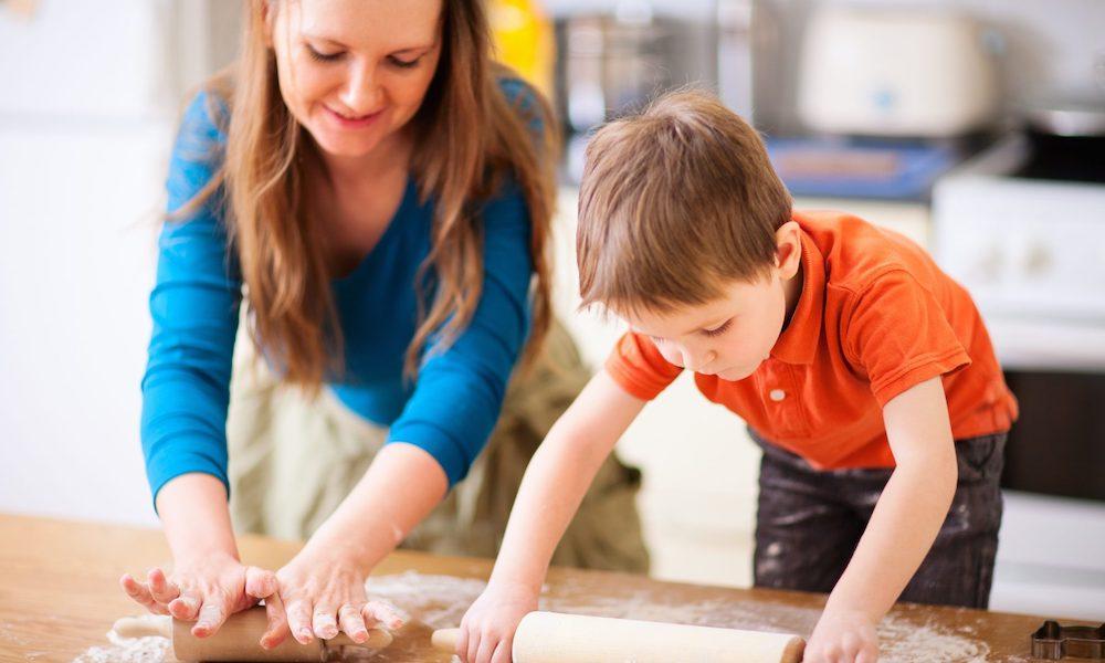 mother rolling dough with young child