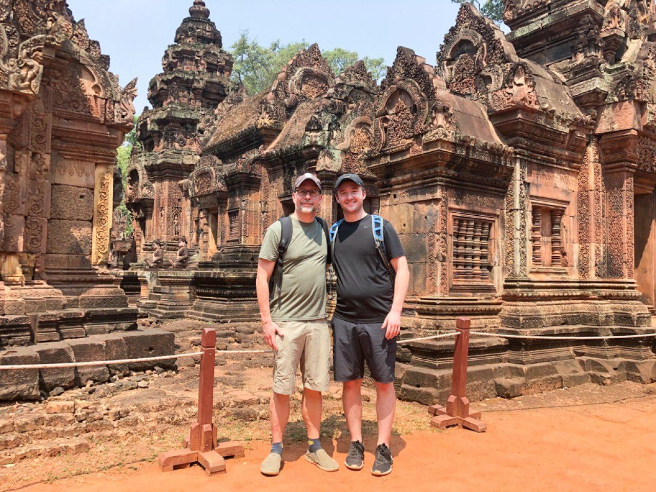 2 men standing in front of monuments in Angkor Wat, Cambodia