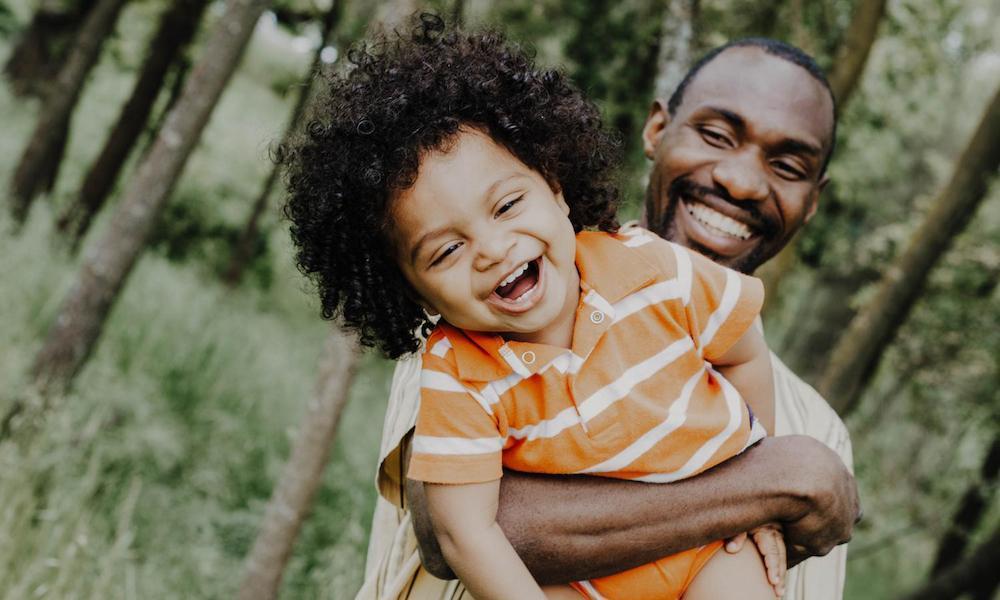Black father holding toddler in a happy embrace