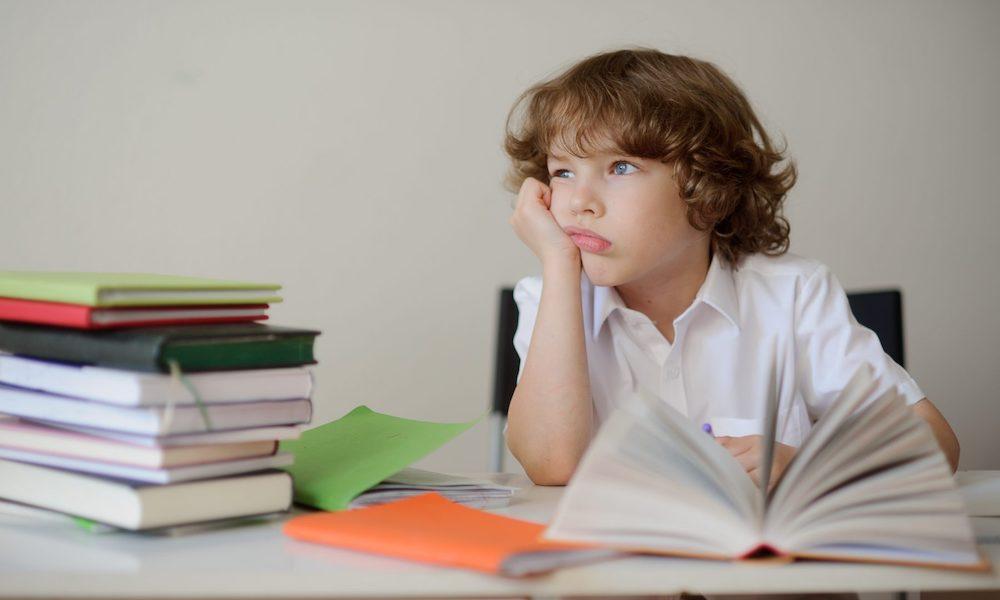elementary school child looking bored with a stack of books