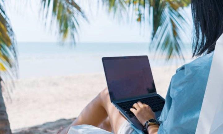 woman at beach working on laptop