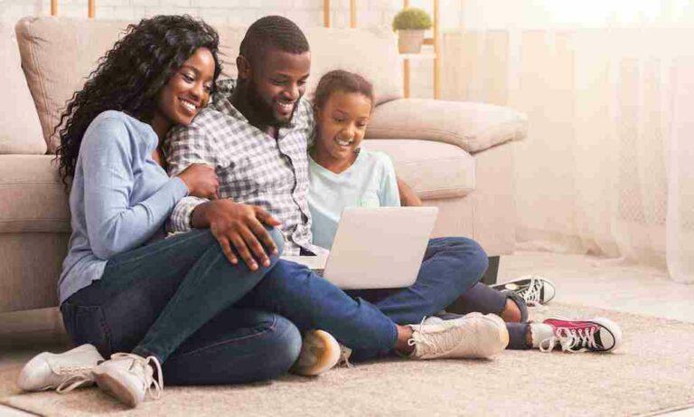 smiling parents and daughter looking at laptop computer together
