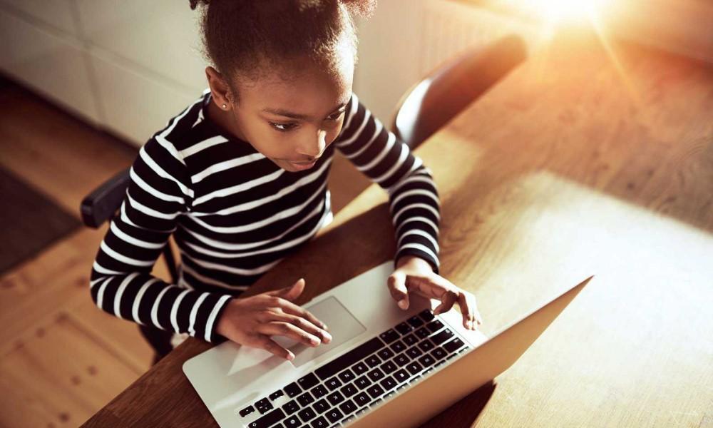young girl typing on laptop
