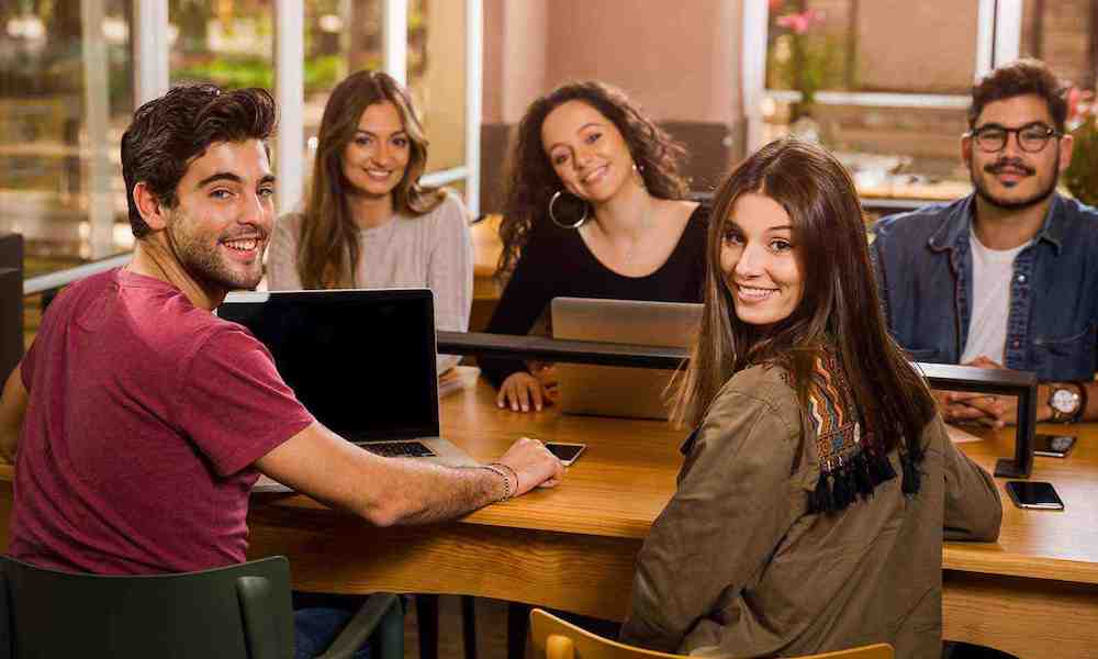 happy college students sitting at table