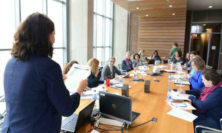 woman presenting information to a colleagues sitting around a conference table