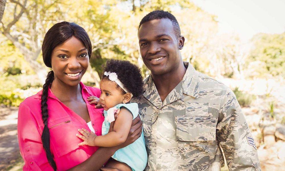 Man in military uniform wiith hand on belly of pregnant wife