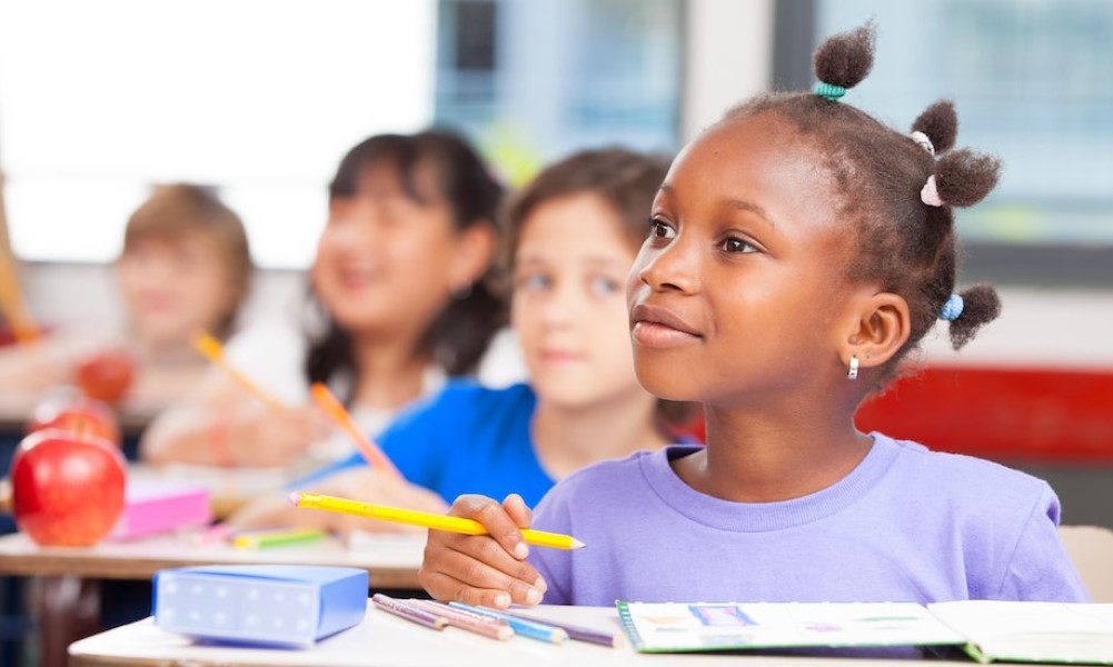 smiling elementary school children sitting at their desks