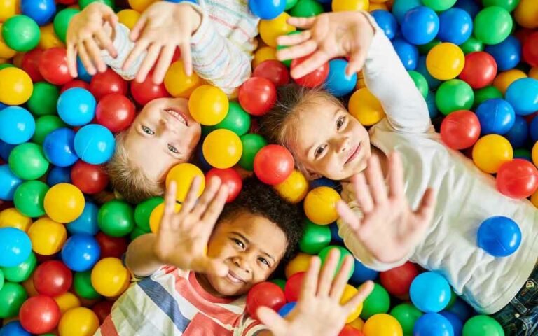 3 smiling kids playing in ball pit