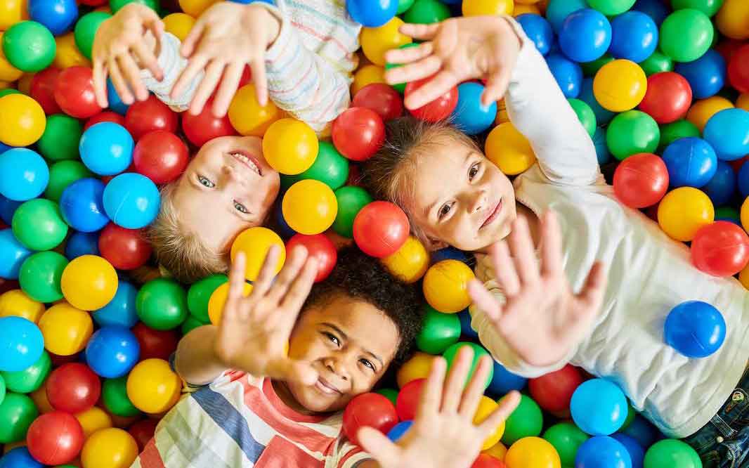 3 smiling kids playing in ball pit