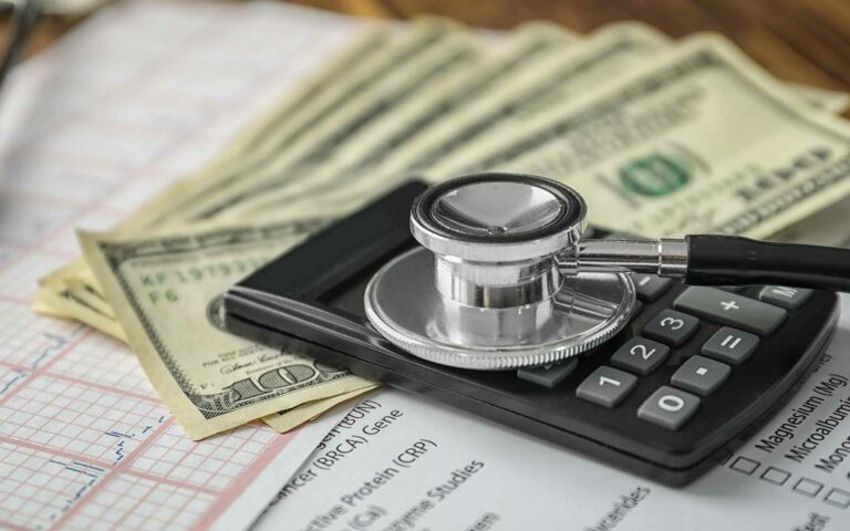 photo of stethoscope on top of medical chart and dollar bills