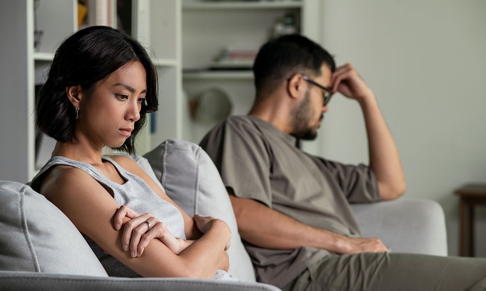 unhappy man and woman sitting on a couch and looking away from each other